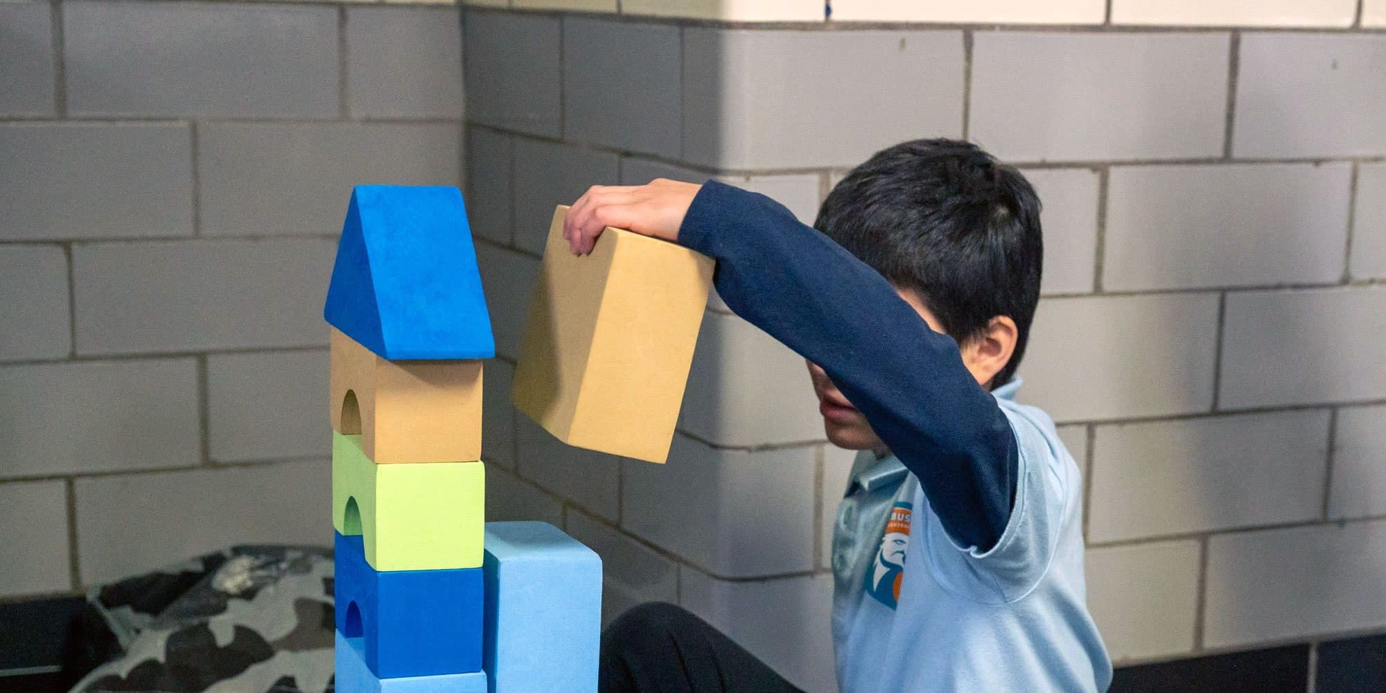 Student stacking colorful foam building blocks.