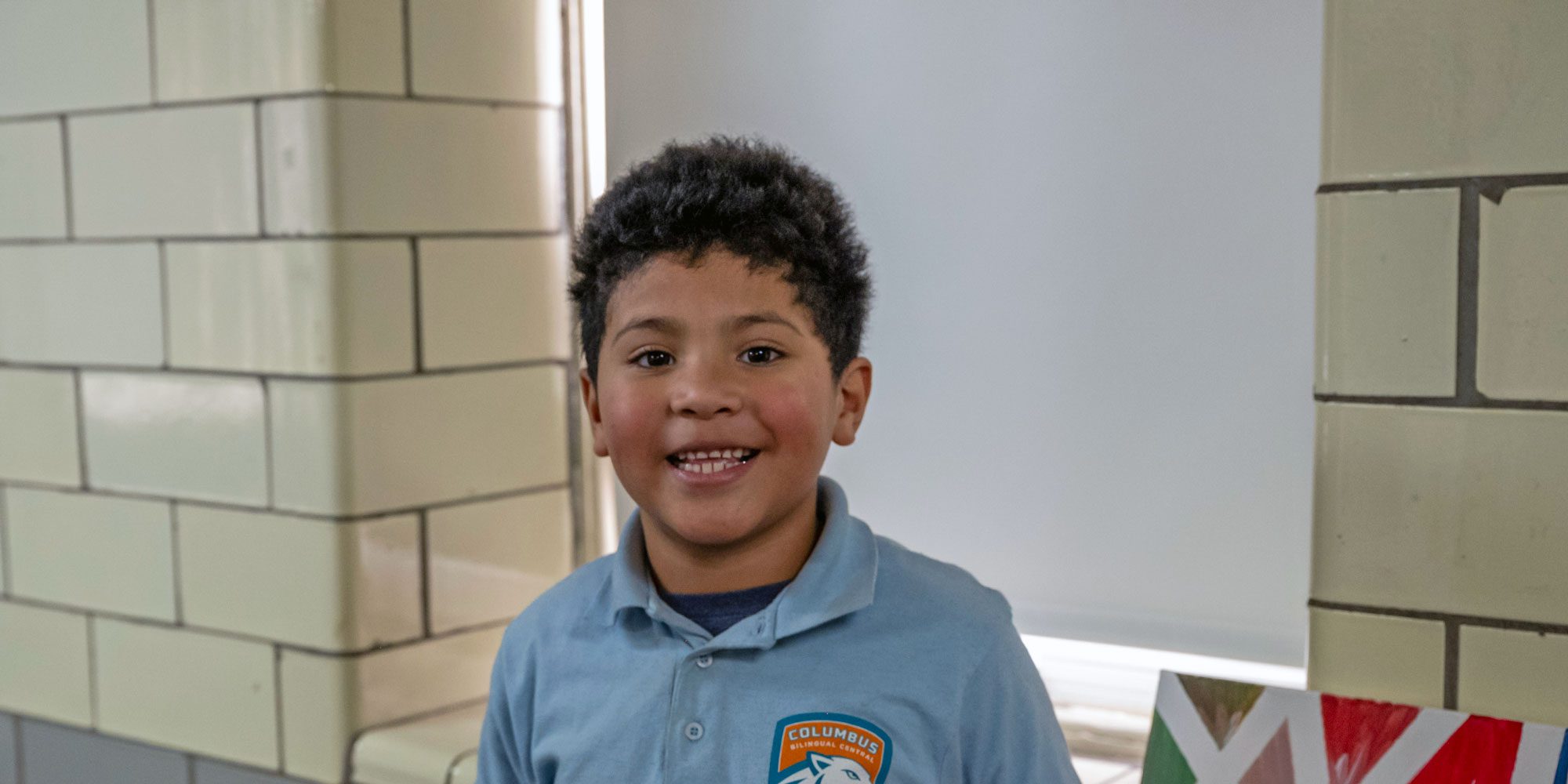 Smiling student in a Columbus Bilingual Central polo shirt.